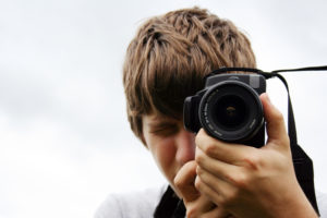 Young photographer holds a camera in front of his face